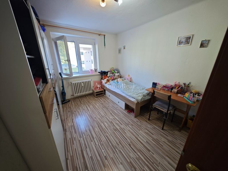 Dětský pokoj s podlahou s dřevěným dekorem v 2-pokojovém bytě plný hraček.