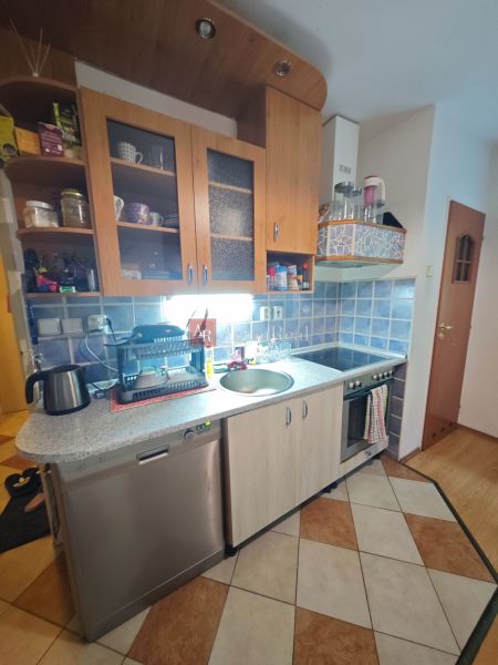 Kuchyně v 2-pokojovém bytě s modrými kachličkami a podlahou s dřevěným dekorem.