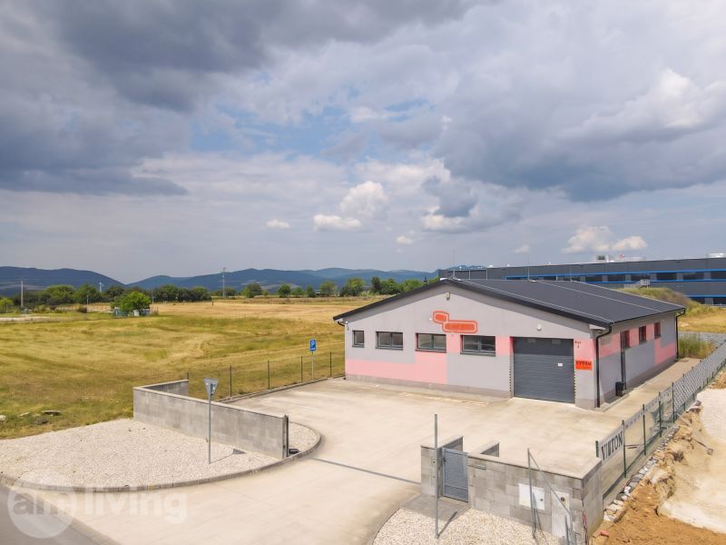 Průmyslová stavba v Nové Dubnici obklopená poli a horami.