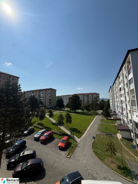 Pohled na sídliště s parkovištěm, stromy a bytovými domy na Mírové ulici ve Staré Ľubovni.