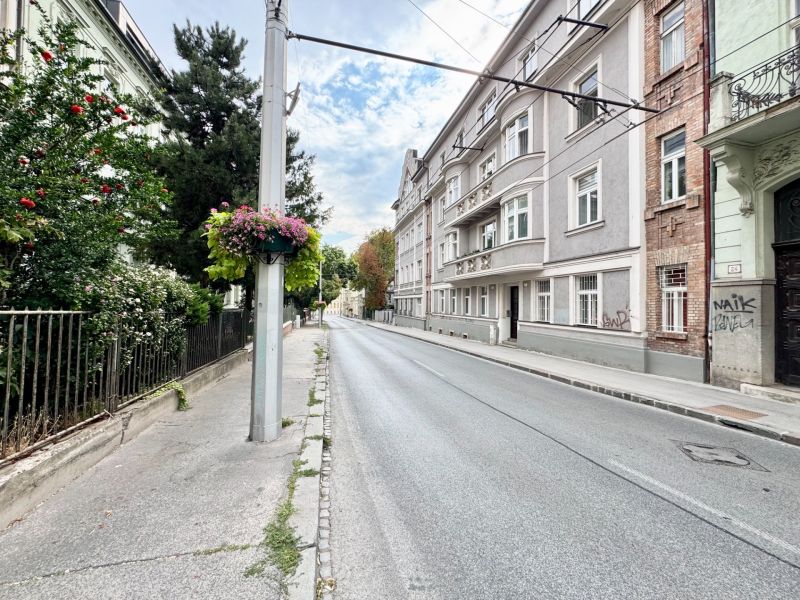 Palisády ve Starém Městě Bratislavy s historickými budovami a květinovou výzdobou na sloupu.