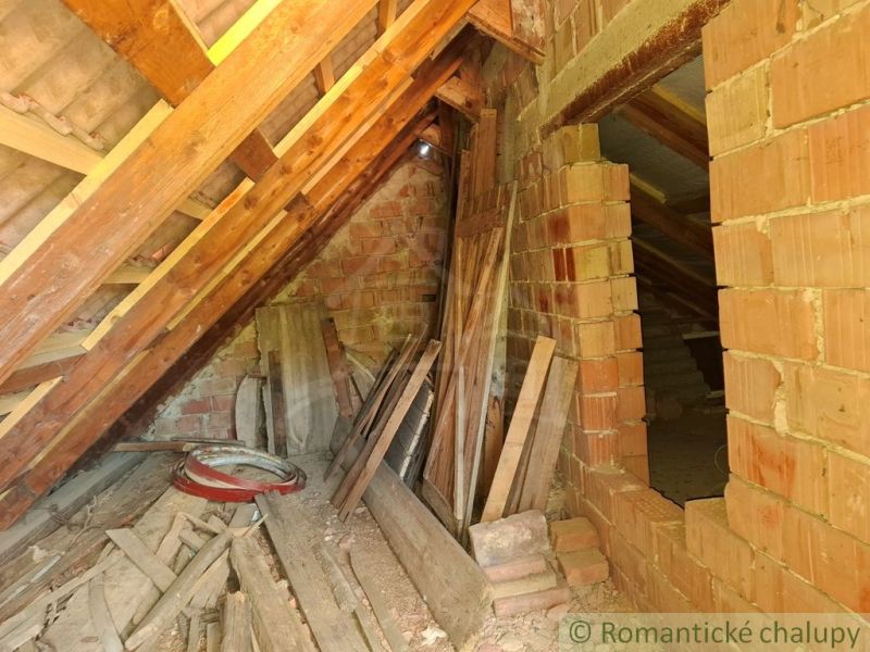 Podkroví se stavebním materiálem v chatě, cihly a dřevěné trámy v Gbelcích.