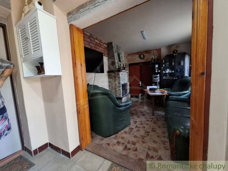 Obývací pokoj v chatě s krbem, koženým posezením a bílou skříňkou.