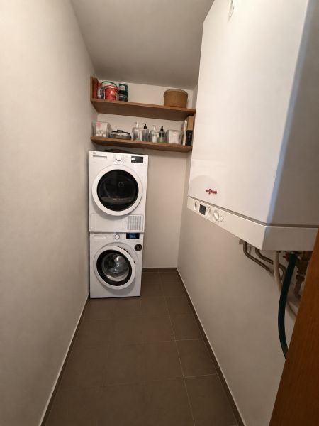 Prádelna v 3-pokojovém bytě s pračkou, sušičkou, policemi a plynovým kotlem.