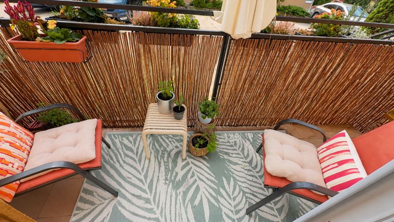 Balkon s květinami a židlemi s polštáři ve 3pokojovém bytě.