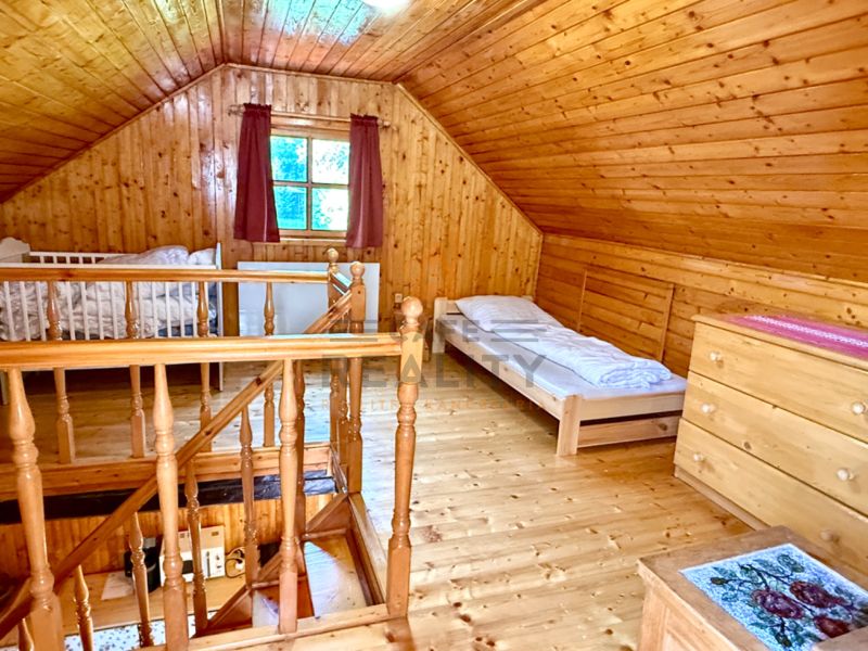 Podkroví rodinného domu s dřevěným obkladem a podlahou s dřevěným dekorem.