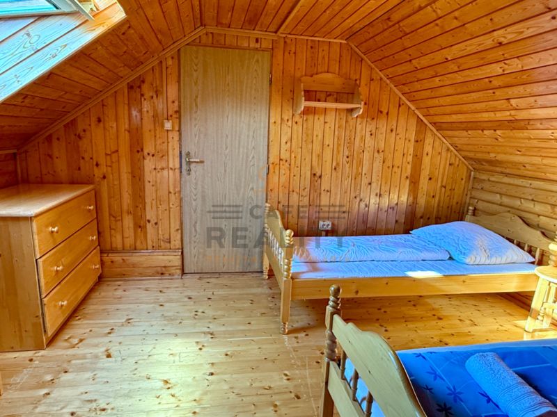 Podkrovní pokoj v rodinném domě s dřevěným dekorem a jednoduchým zařízením.