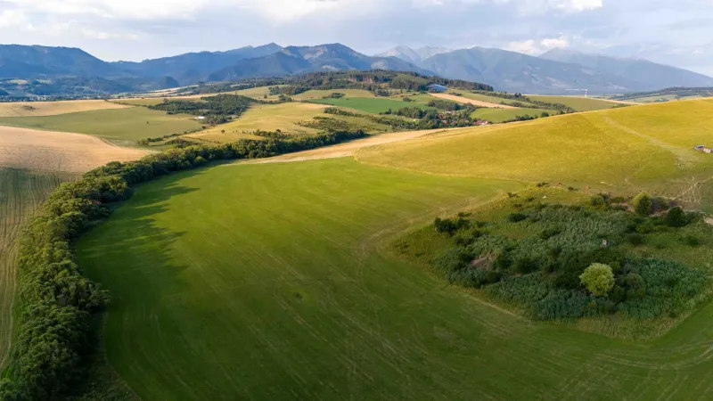 Pohled na rozlehlá pole v Liptovském Trnovci s horami. Zvláštní nemovitosti.