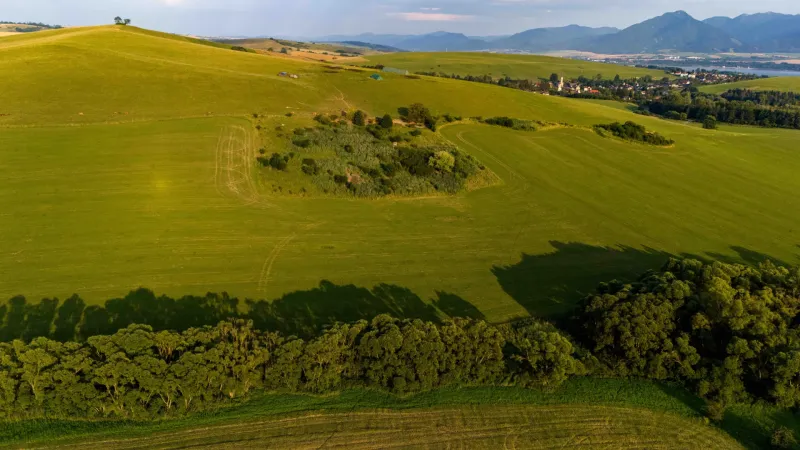 Zelené louky a stromy s výhledem na vesnici v Liptovském Trnovci, zvláštní nemovitosti.