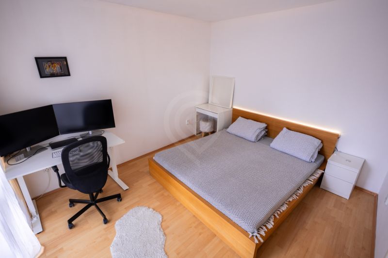 Ložnice s postelí, pracovním stolem a podlahou s dřevěným dekorem ve 4pokojovém bytě.
