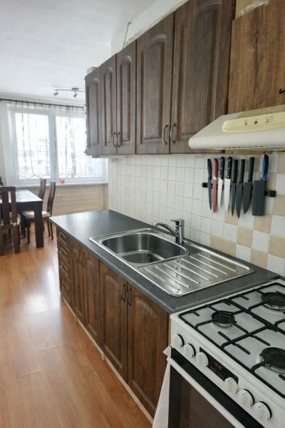 Kuchyně v 3-pokojovém bytě s podlahou s dřevěným dekorem a stylovými skříňkami.