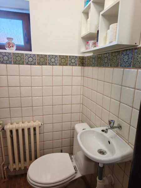 Koupelna v rodinném domě s toaletou, umyvadlem a oknem, obložená kachličkami.