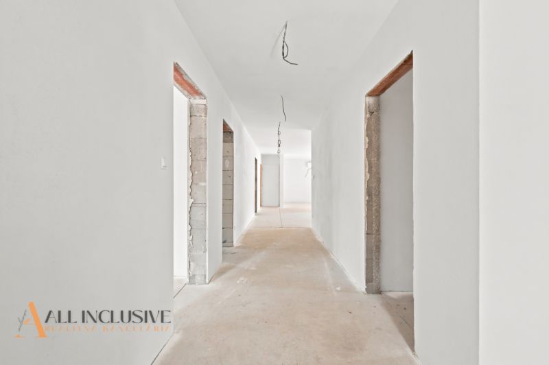 Chodba v rodinném domě s bílými stěnami, rozestavěné dveřní otvory.