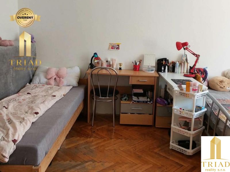 Studentský pokoj v garsonce s podlahou s dřevěným dekorem a jednoduchým nábytkem.