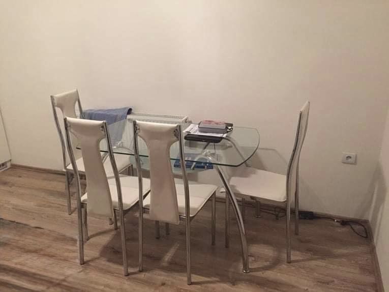 Skleněný jídelní stůl s bílými židlemi na podlaze s dřevěným dekorem.