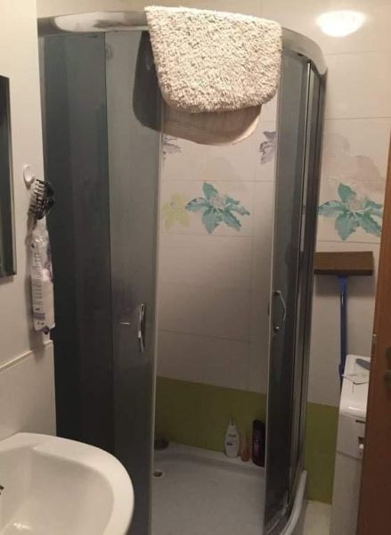 Koupelna v 2-pokojovém bytě se sprchovým koutem a dekorativní dlažbou.