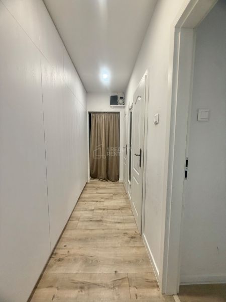 Chodba s bílými stěnami a podlahou s dřevěným dekorem ve 3-pokojovém bytě.