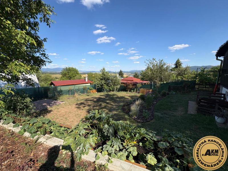 Zahrada ve Zvolenu s výhledem na kopce, trávníkem a altánkem pod modrou oblohou.