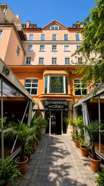 Restaurace na Hviezdoslavově náměstí v Bratislavě - Starém Městě, obklopená zelení a palmami.