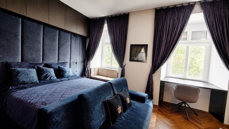 Luxusní ložnice s tmavými závěsy a pracovním stolem v 2pokojovém bytě.