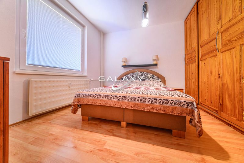 Ložnice s šatníkem a podlahou s dřevěným dekorem v 2-pokojovém bytě.