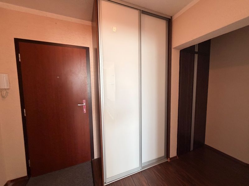 Předsíň v 3-pokojovém bytě s bílou šatní skříní a podlahou s dřevěným dekorem.