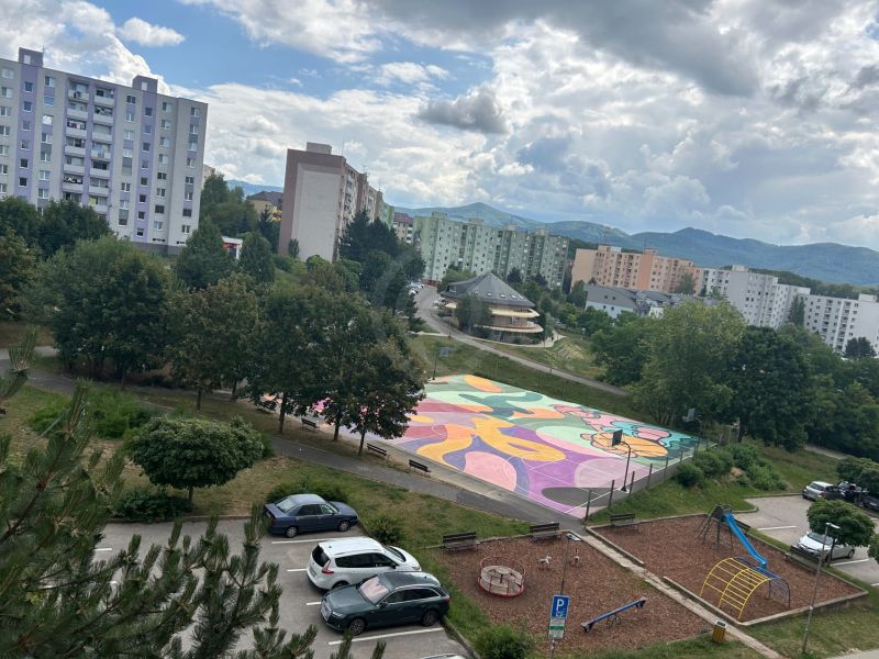Pohled na barevné hřiště, hřiště a paneláky na Mateja Bela v Trenčíně.