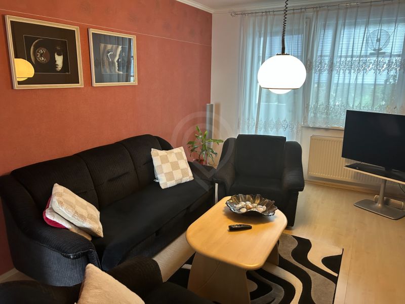 Obývací pokoj ve 3pokojovém bytě s pohovkou, stolkem a dekoracemi na stěně.