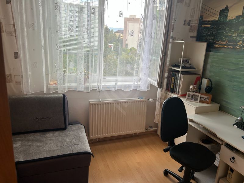 Pracovní kout v 3-pokojovém bytě s podlahou s dřevěným dekorem a psacím stolem.