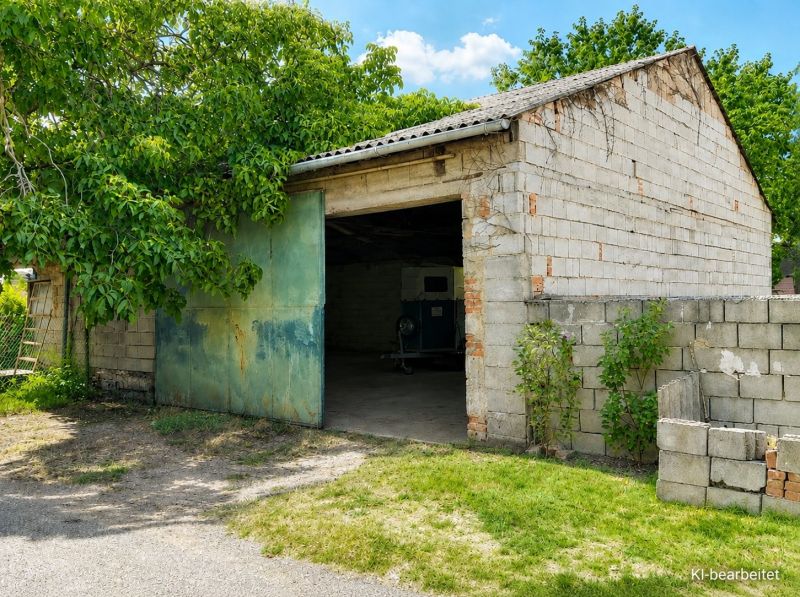 Rodinný dům v Illmitzi má cihlovou garáž se zelenými dveřmi a okolní zelení.