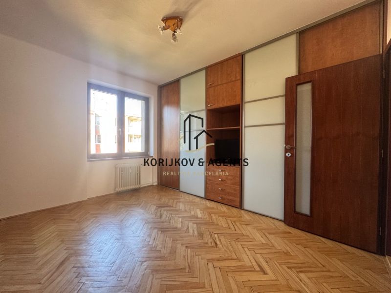 Pokoj s vestavěnou skříní a podlahou s dřevěným dekorem ve 4pokojovém bytě.