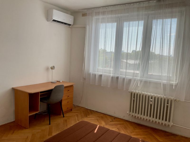 Pokoj v 2-pokojovém bytě s psacím stolem, židlí a klimatizací.
