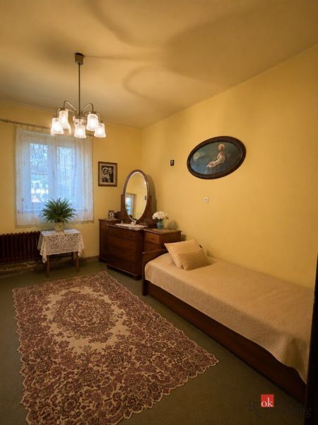 Pokoj v rodinném domě s kobercovou podlahou, žlutými stěnami, postelí a zrcadlem.