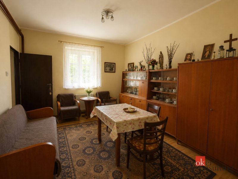 Obývací pokoj s dřevěným nábytkem, podlahou s dřevěným dekorem, kobercem a dekoračními předměty.