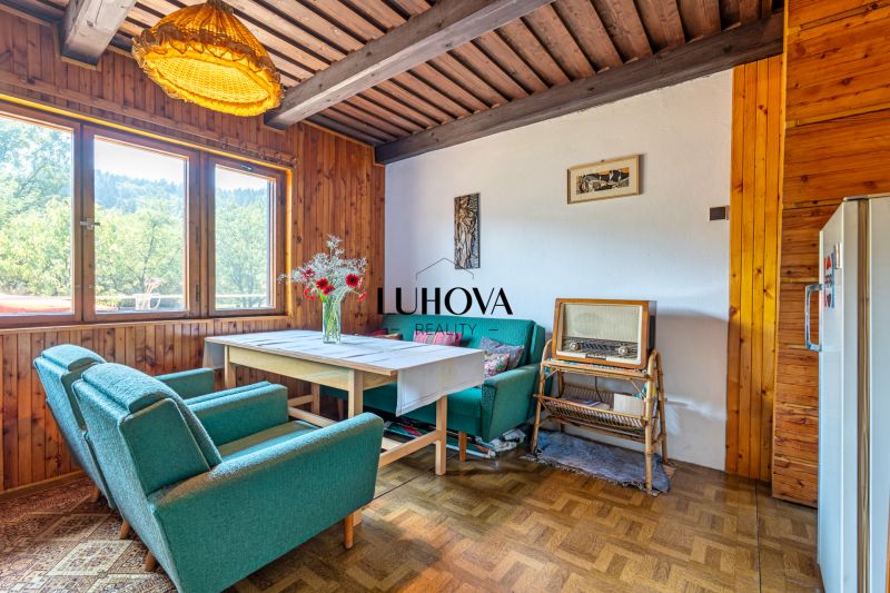 Interiér chaty s retro nábytkem a podlahou s dřevěným dekorem, pohodlná křesla, vintage rádio.