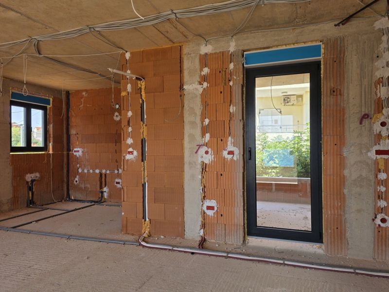 Rozestavěný 3-pokojový byt s cihlovými stěnami a elektroinstalací připravenou na montáž.