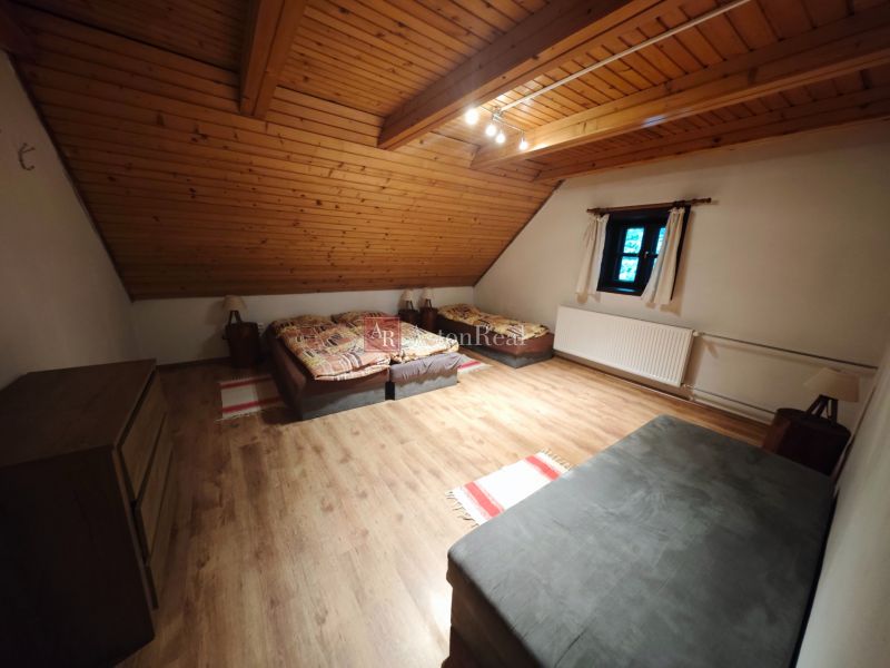 Pokoj se třemi postelemi, podlahou s dřevěným dekorem a šikmým dřevěným stropem v chatě.