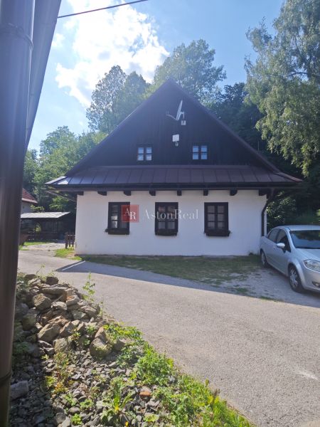Chata ve Španí Dolině s bílou fasádou a satelitní anténou, obklopená zelení.