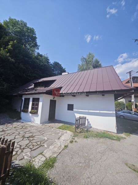 Rodinný dům ve Španí Dolině s kamenným chodníkem a dřevěným plotem obklopený přírodou.
