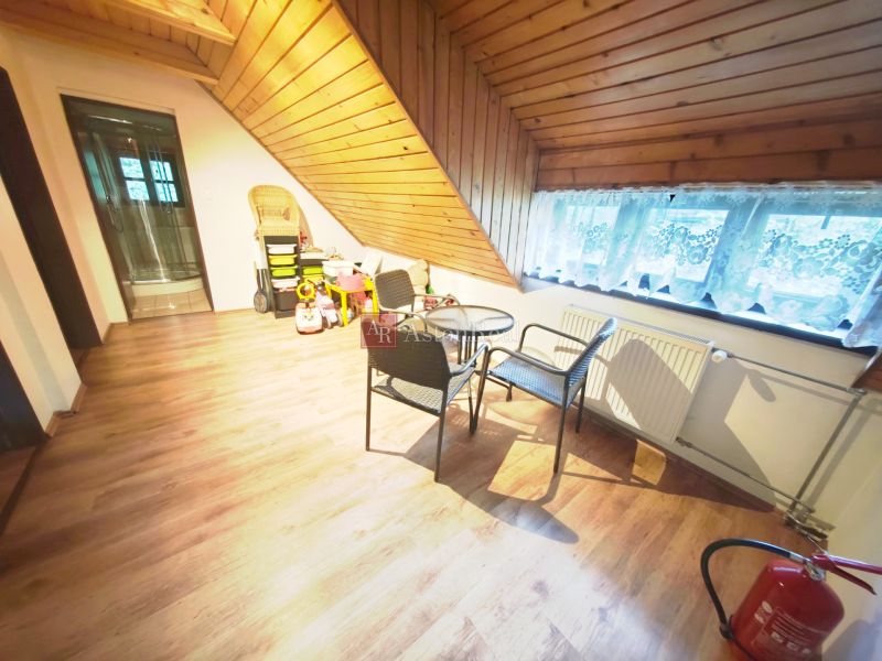 Podlaha s dřevěným dekorem, sezení, dětské hračky a šikmý strop v chatě.
