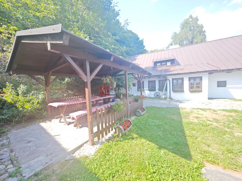 Chata ve Španí Dolině s altánkem, dřevěným stolem a květinovou výzdobou na zahradě.
