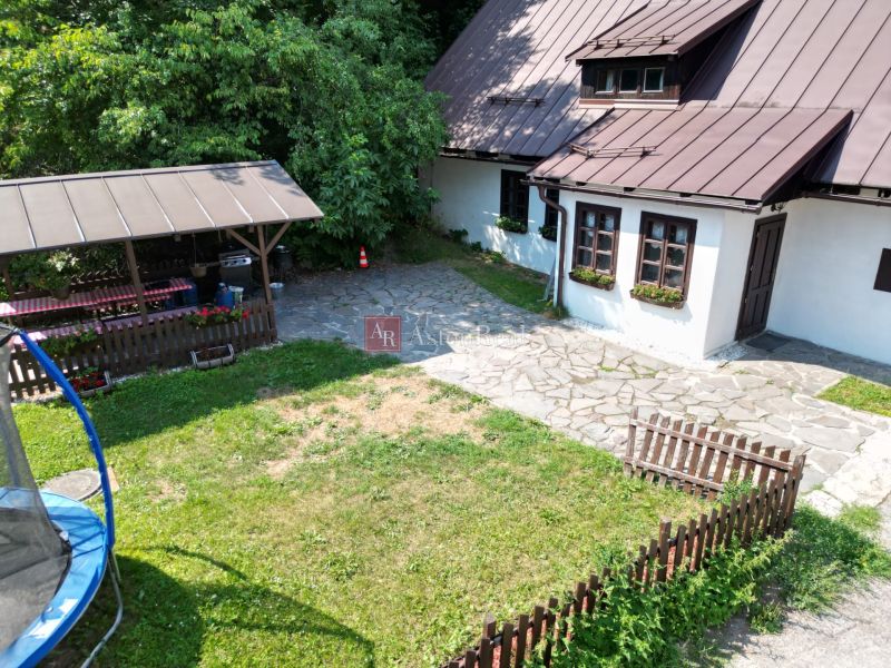 Rodinný dům ve Španí Dolině se zahradou, trávníkem, trampolínou a dřevěným altánkem v přírodě.