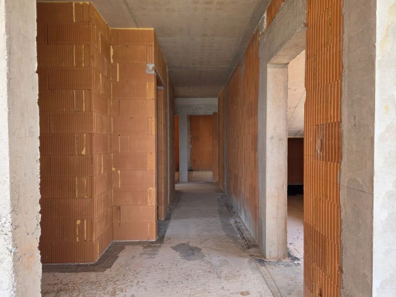 Hrubá stavba 4pokojového bytu s cihlovými stěnami a betonovým stropem.