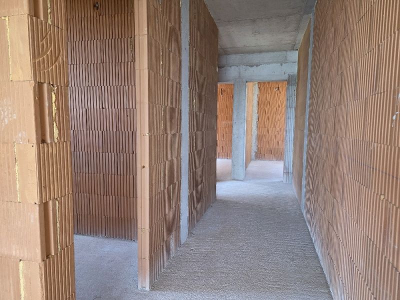 Interiér 4-pokojového bytu s holými cihlovými stěnami a cementovou podlahou.
