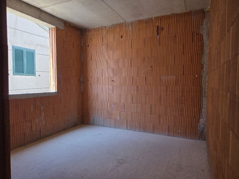 Neúplná místnost s cihlovými stěnami, součást 4-pokojového bytu.