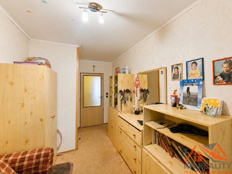 Interiér rodinného domu s dřevěným nábytkem, koberec a fotografie na stěně.