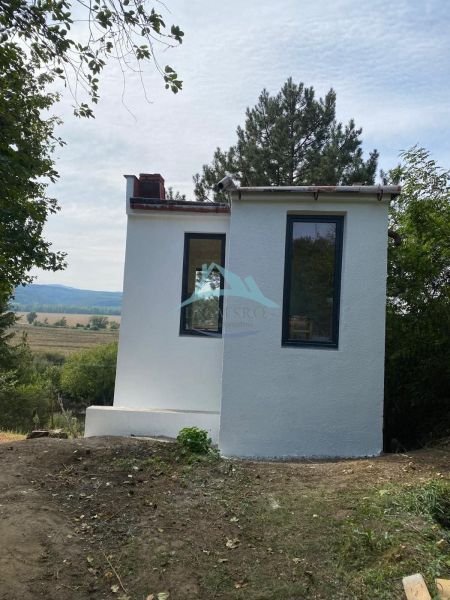 Malá chata v Šahách, obklopená stromy a krásnou přírodou.