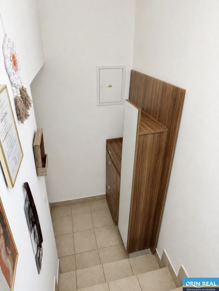Schodiště s úložným prostorem v 1-pokojovém bytě, bílá stěna, dřevěný dekor.