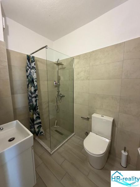 Koupelna v garsonce s WC, sprchovým koutem a umyvadlem.