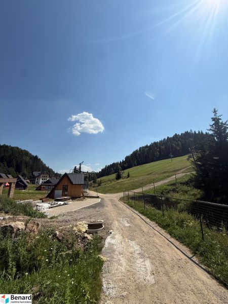 Rekreační pozemky v Litmanové se scenérií lesa a domů, modré nebe.